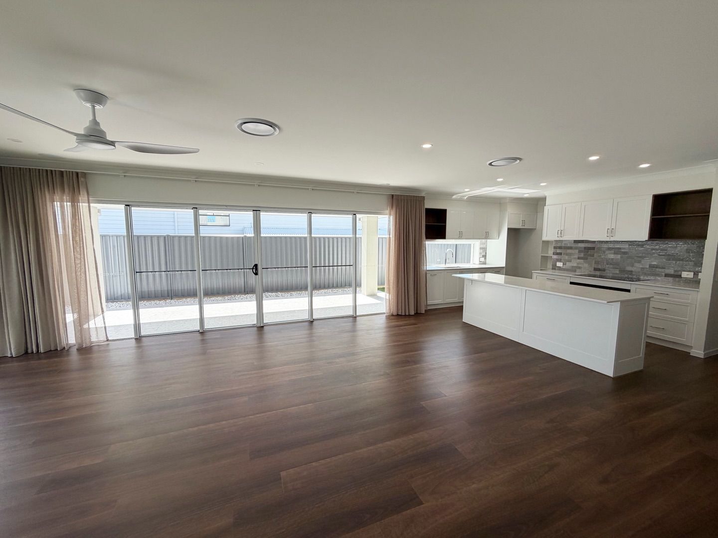 Open-plan living room with wood floors, white kitchen island — Totally Flooring Gold Coast In Bundall, QLD