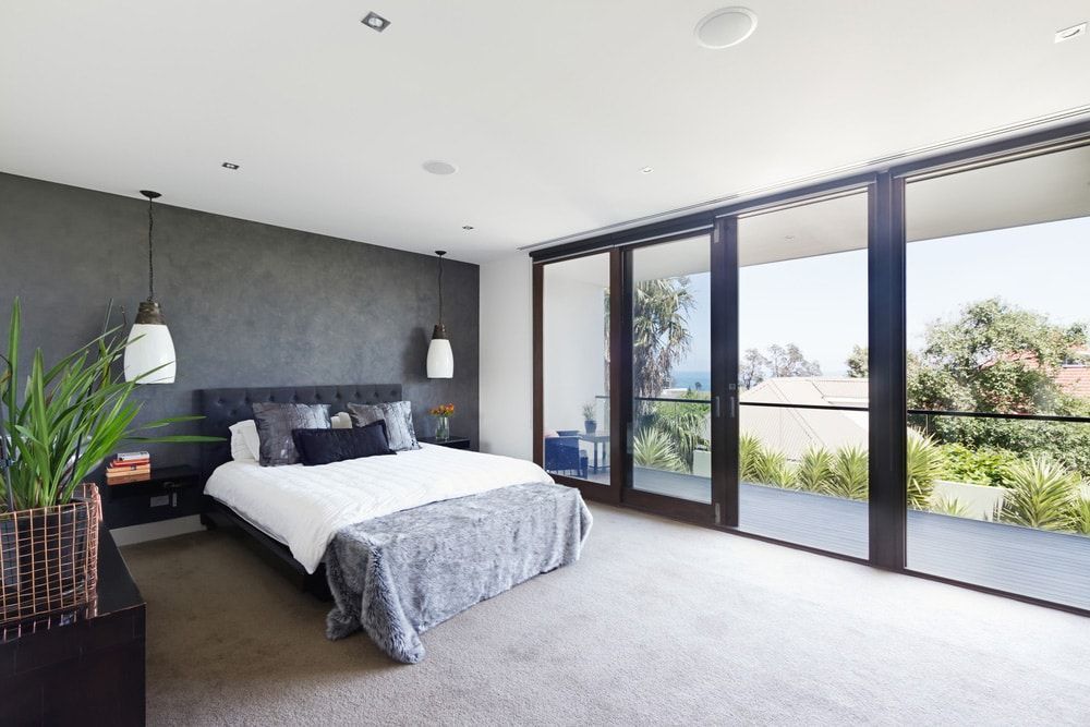 A Bedroom With a Large Bed and Sliding Glass Doors Leading to a Balcony — Totally Flooring Gold Coast In Browns Plains, QLD