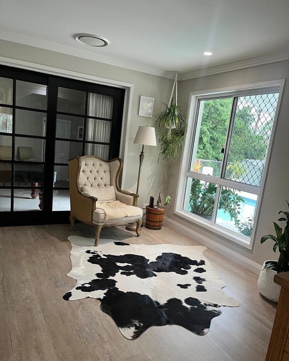 A Living Room With a Cowhide Rug, Chair, Lamp and Sliding Glass Doors — Totally Flooring Gold Coast In Bundall, QLD