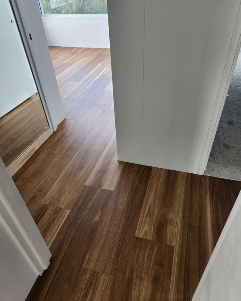 A Hallway With a Wooden Floor and a Mirror — Totally Flooring Gold Coast In Bundall, QLD