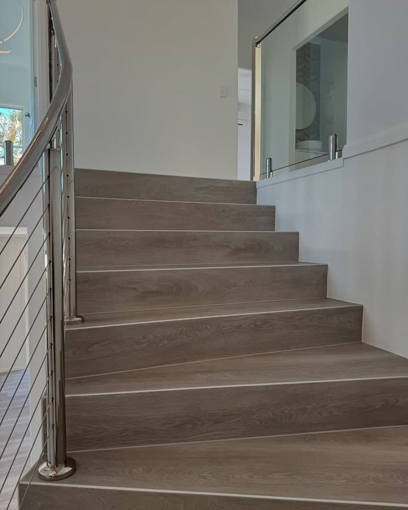 A Set of Stairs With a Stainless Steel Railing and a Glass Railing — Totally Flooring Gold Coast In Bundall, QLD