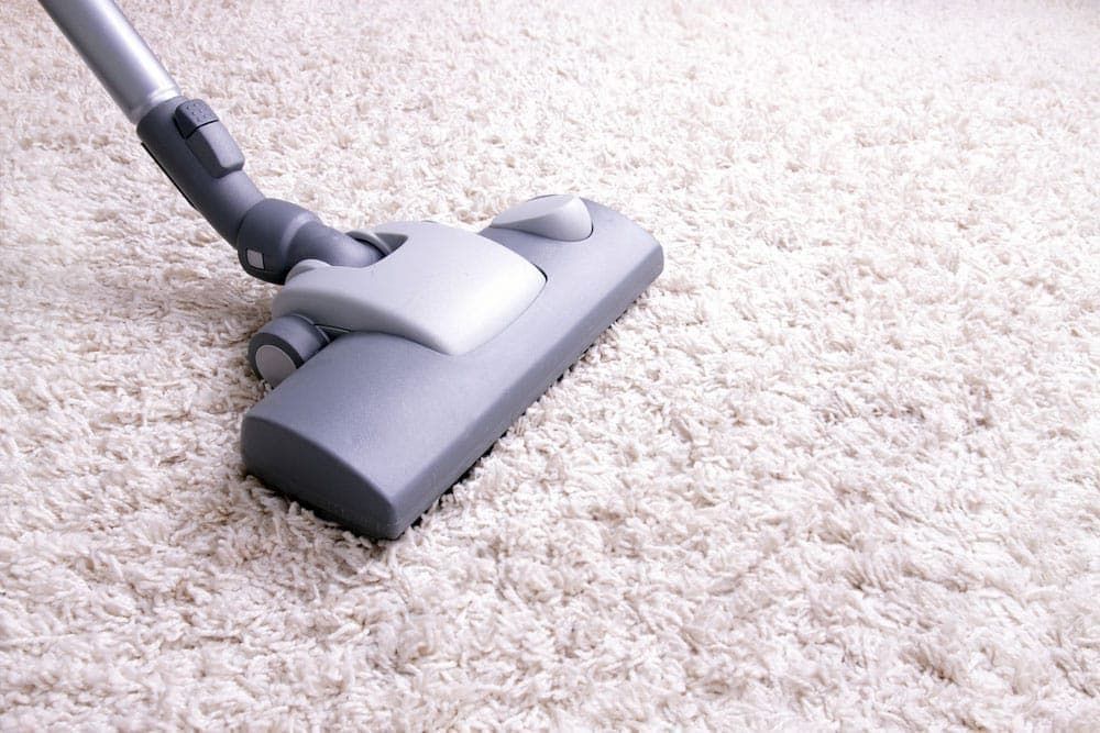 A Vacuum Cleaner is Being Used to Clean a White Carpet — Totally Flooring Gold Coast In Bundall, QLD