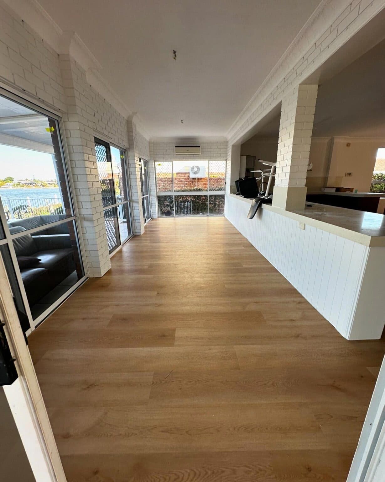 A Large Empty Room With a Wooden Floor and a Lot of Windows — Totally Flooring Gold Coast In Bundall, QLD