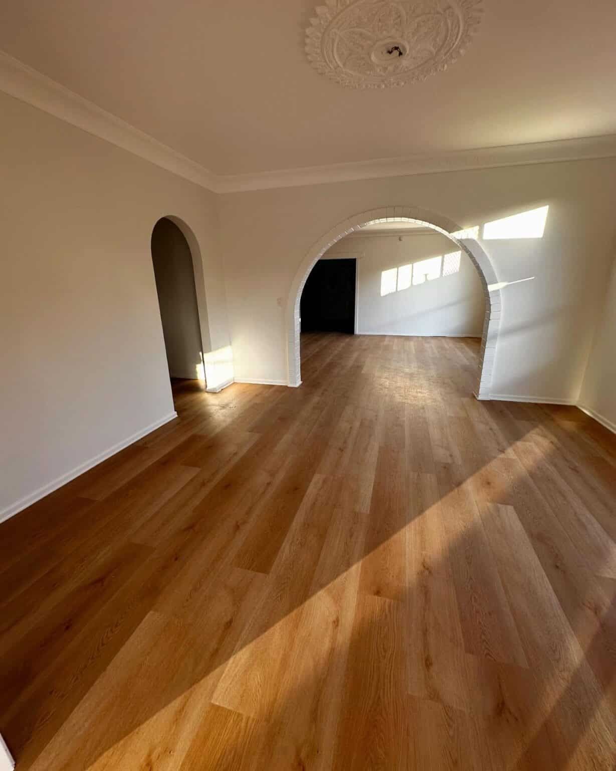 An Empty Living Room With Hardwood Floors and White Walls — Totally Flooring Gold Coast In Bundall, QLD