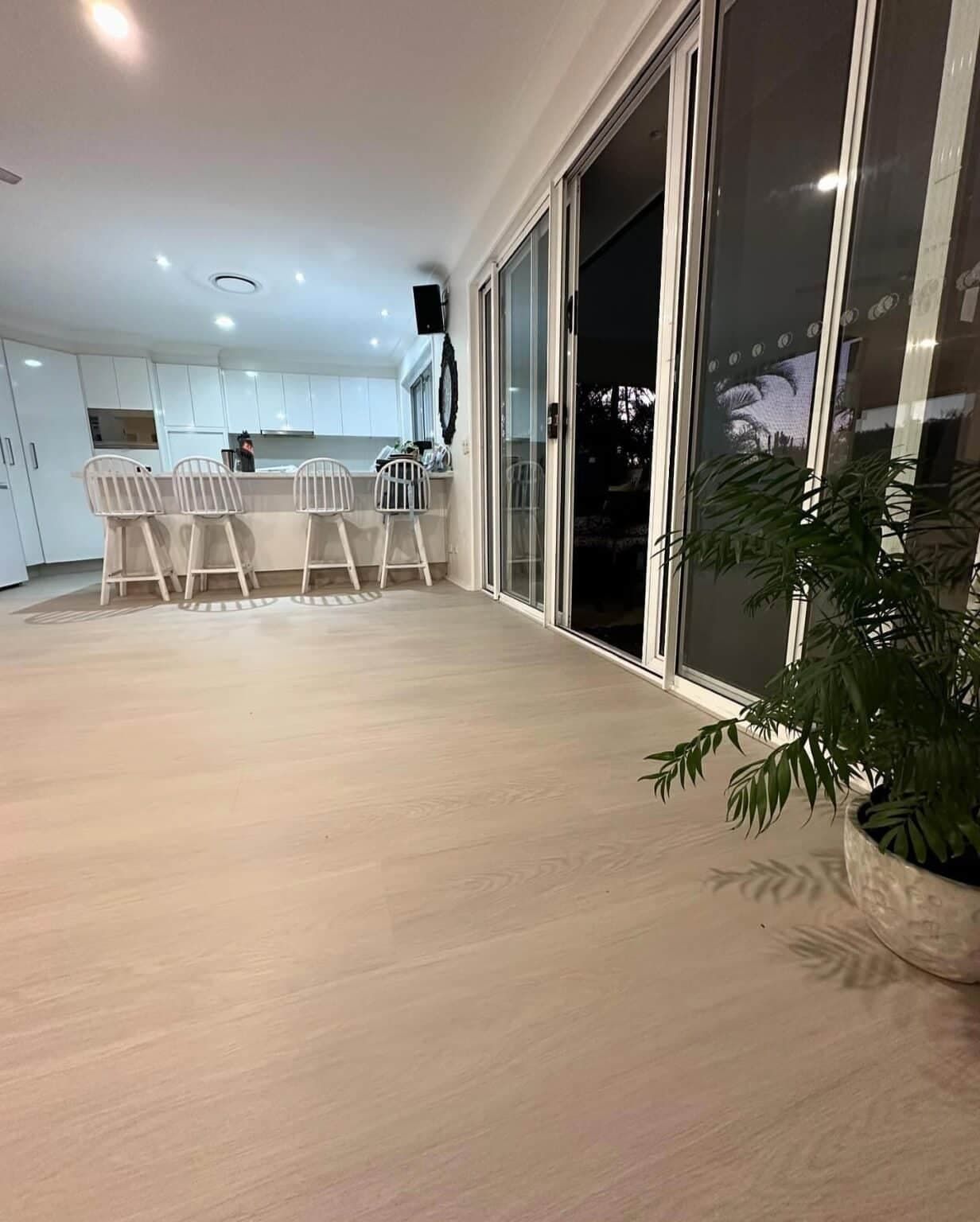 A Living Room With Sliding Glass Doors Leading to a Kitchen — Totally Flooring Gold Coast In Bundall, QLD