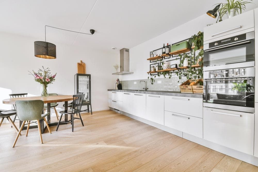 A Kitchen With White Cabinets, Wooden Floors, a Table and Chairs — Totally Flooring Gold Coast In Bundall, QLD
