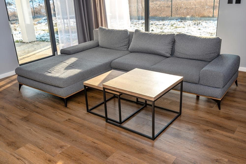 A Living Room With a Sectional Couch and Two Coffee Tables — Totally Flooring Gold Coast In Bundall, QLD