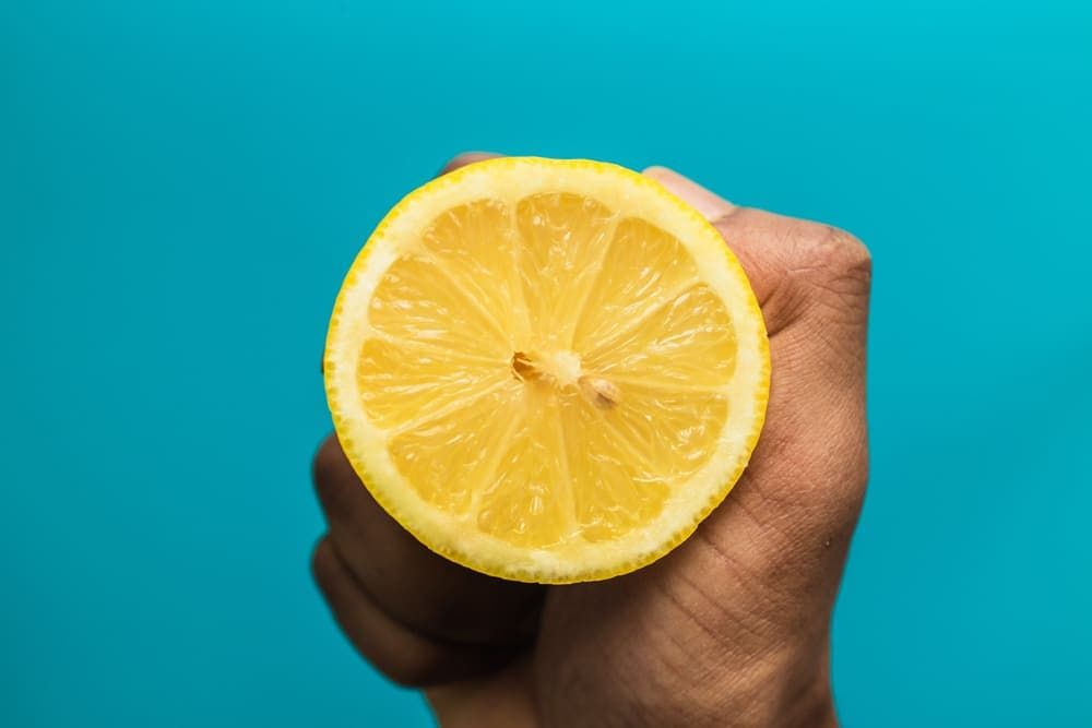 A Person is Holding a Slice of Lemon in Their Hand — Totally Flooring Gold Coast In Bundall, QLD