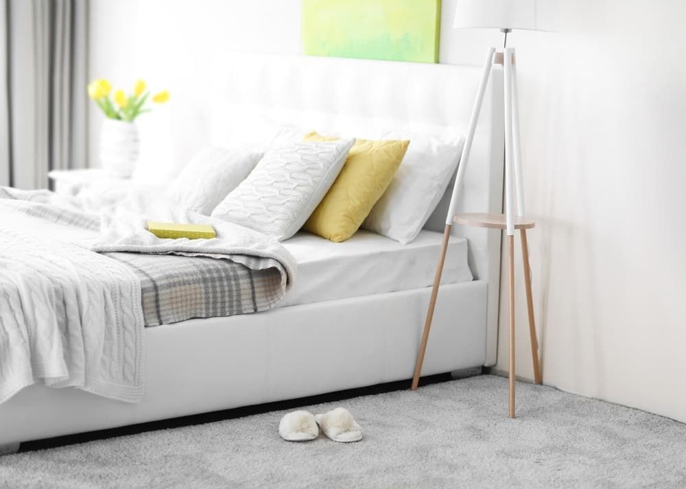 A Bedroom With a Bed, Lamp and Slippers on the Floor — Totally Flooring Gold Coast In Bundall, QLD
