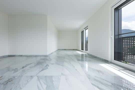 An Empty Living Room With a Marble Floor and a Balcony — Totally Flooring Gold Coast In Bundall, QLD