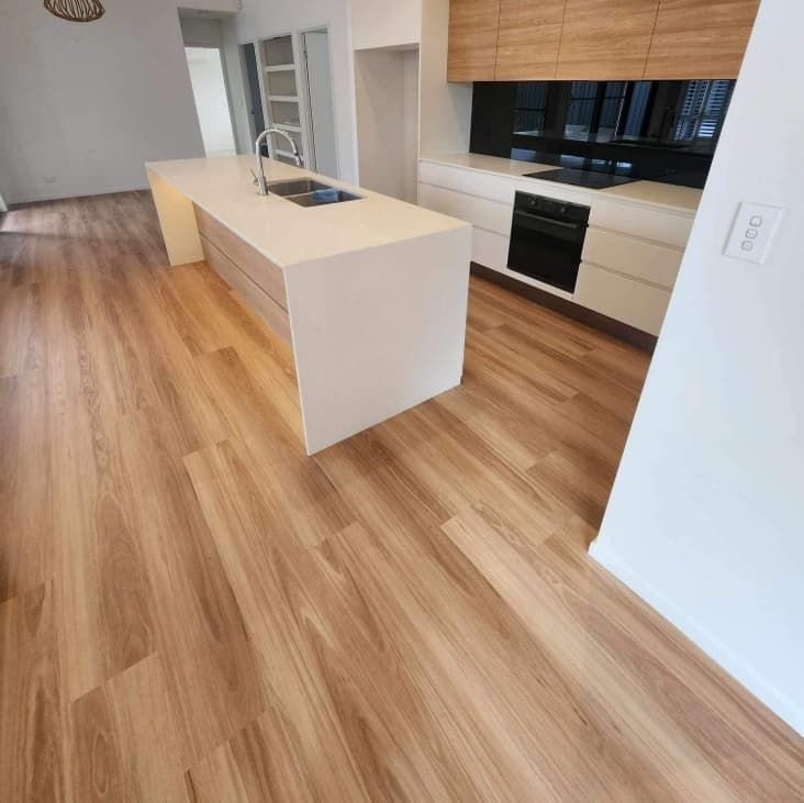 A Kitchen With Wooden Floors and White Cabinets — Totally Flooring Gold Coast In Bundall, QLD