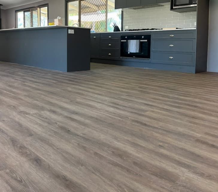 A Kitchen With a Wooden Floor and Gray Cabinets — Totally Flooring Gold Coast In Bundall, QLD