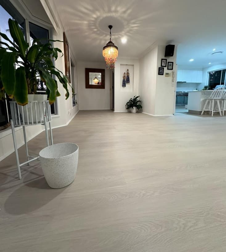 A Living Room With a Wooden Floor and a Potted Plant on the Floor — Totally Flooring Gold Coast In Bundall, QLD