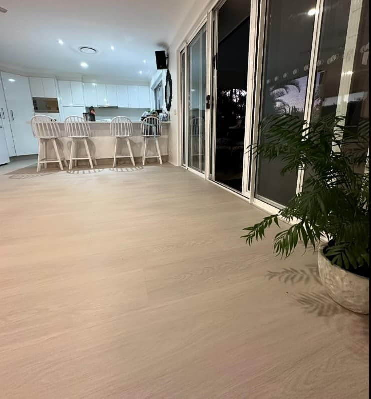A Living Room With a Sliding Glass Door Leading to a Kitchen — Totally Flooring Gold Coast In Bundall, QLD