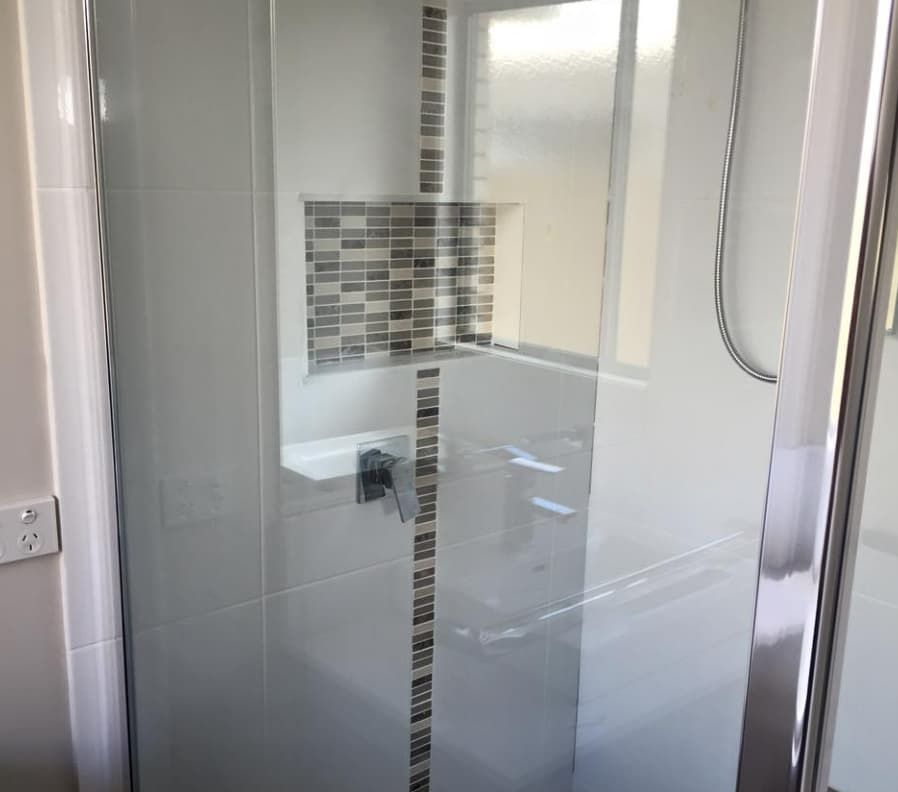 A Bathroom With a Glass Shower Door and a Sink — Totally Flooring Gold Coast In Bundall, QLD