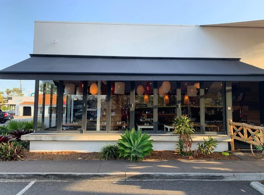 A White Building With a Black Awning on the Front of It — Totally Flooring Gold Coast In Bundall, QLD