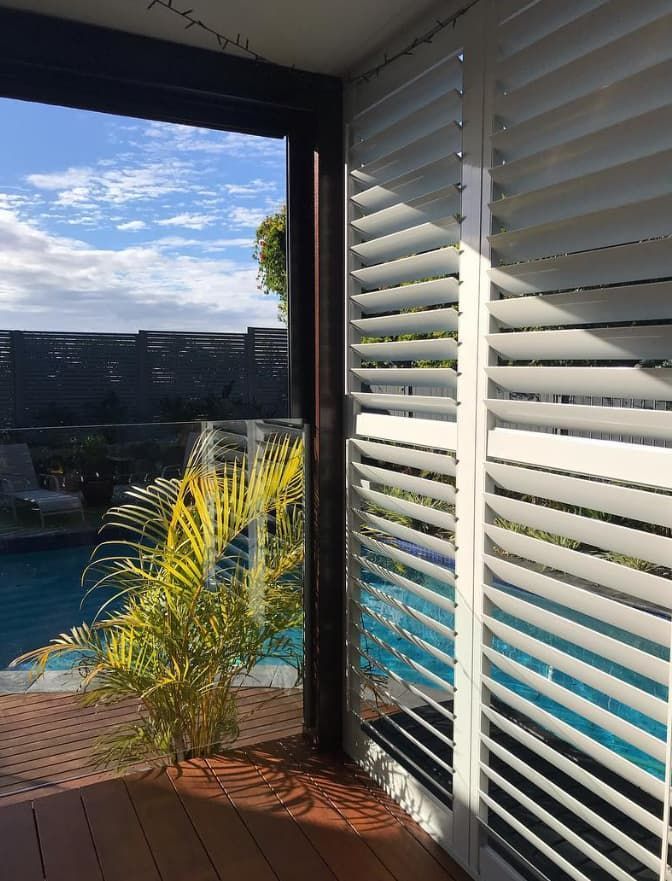 A View of a Swimming Pool Through a Window With Shutters — Totally Flooring Gold Coast In Bundall, QLD