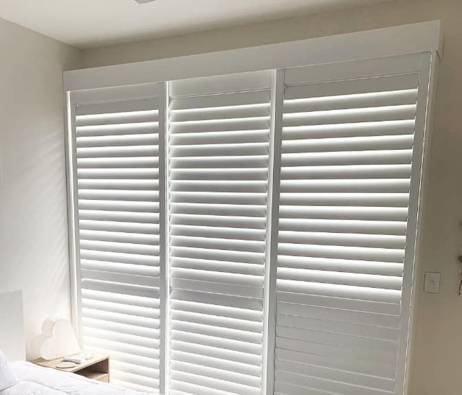 A Bedroom With White Shutters on the Windows and a Bed — Totally Flooring Gold Coast In Bundall, QLD