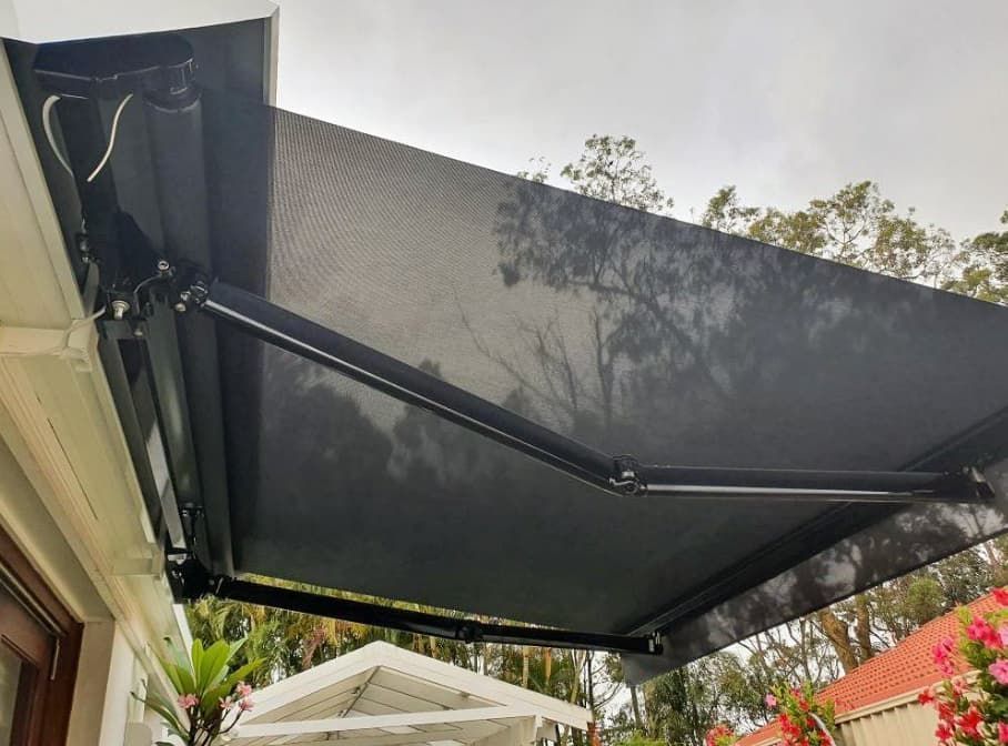 A black awning is hanging from the side of a house.
