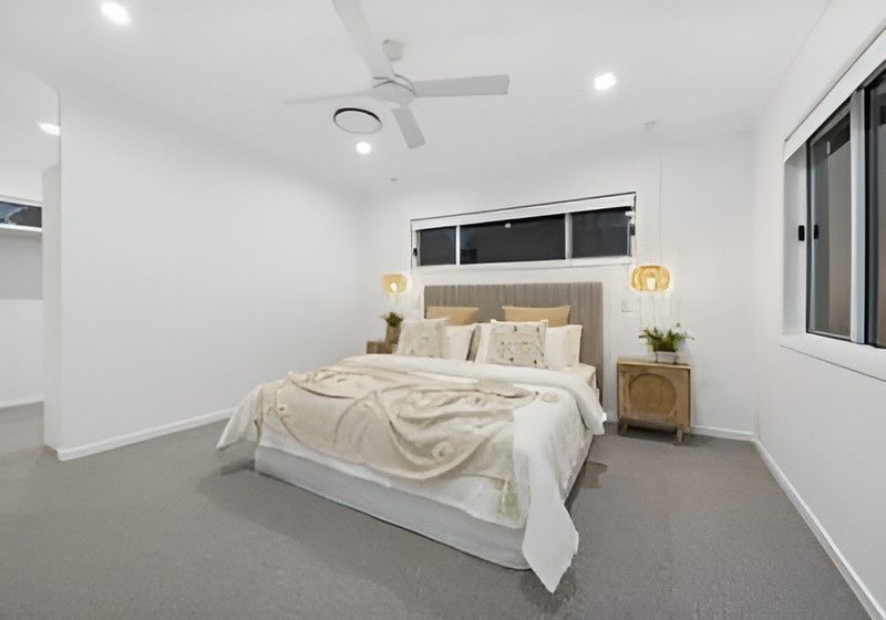 Bright Modern Bedroom with A Neatly Made Bed, White Walls, Gray Carpet, and Bedside Lamps — Totally Flooring Gold Coast In Bundall, QLD