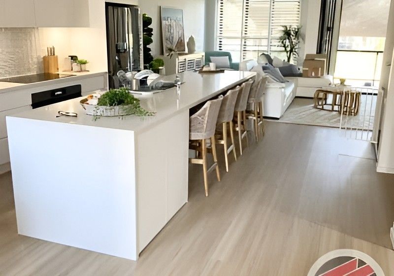 Bright Modern Kitchen with A Large White Island, Bar Stools, and Open Living Space with Natural Light — Totally Flooring Gold Coast In Bundall, QLD