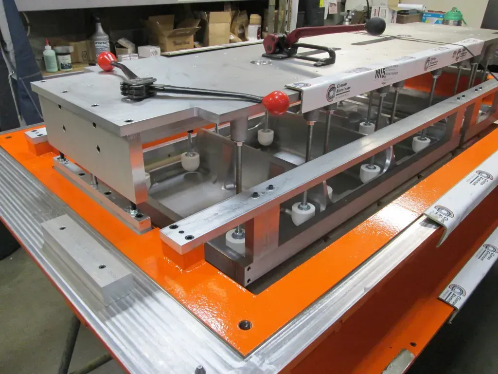 Industrial metal machine on an orange base, with gray panels and wiring in a workshop.