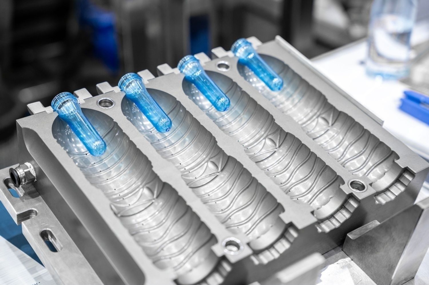 Blue-capped water bottles on a packaging conveyor in a factory machine