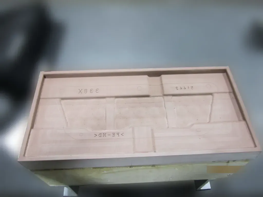 Top view of a light wood box with compartment dividers and handwritten labels on the lid