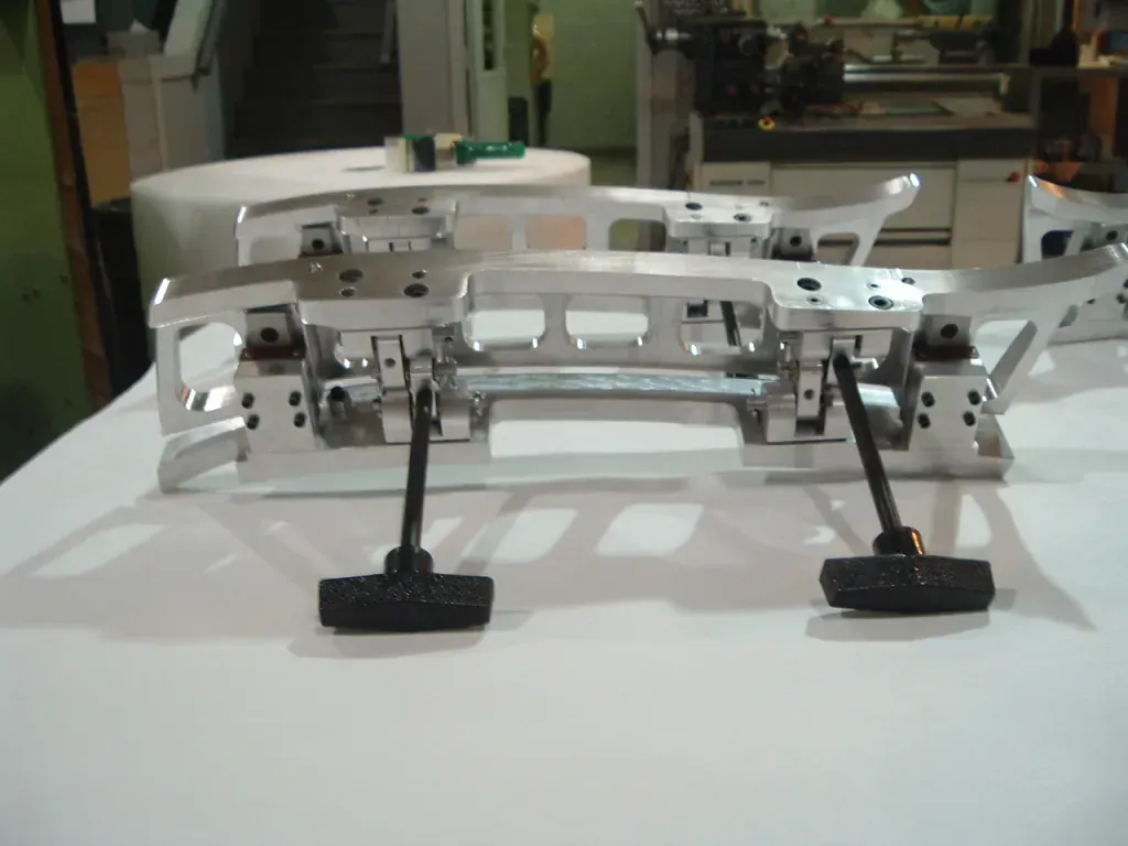 White mechanical robot chassis with four black feet on a table in a workshop