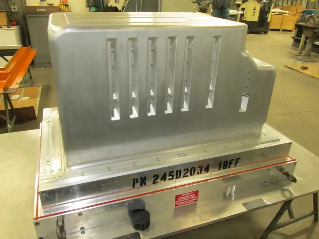 Large silver metal machine component on a workbench in an industrial workshop