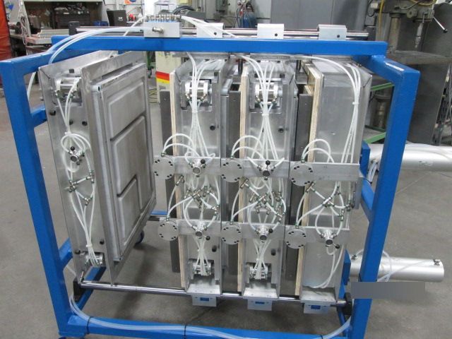 Blue-framed industrial machine with multiple silver pneumatic units and hoses in a factory setting