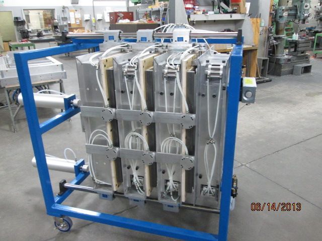 Blue metal rack holding stacked industrial equipment in a factory workshop, with machinery in the background
