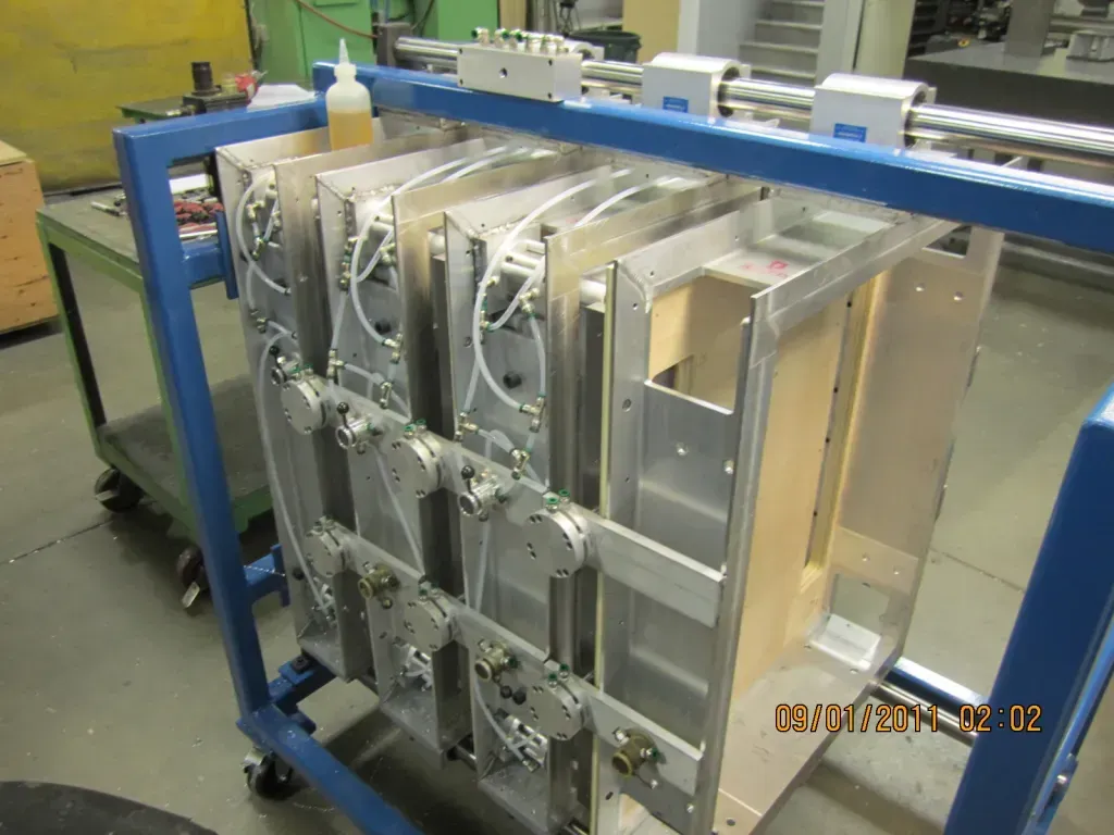 Blue metal industrial machine with stacked silver panels in a factory setting