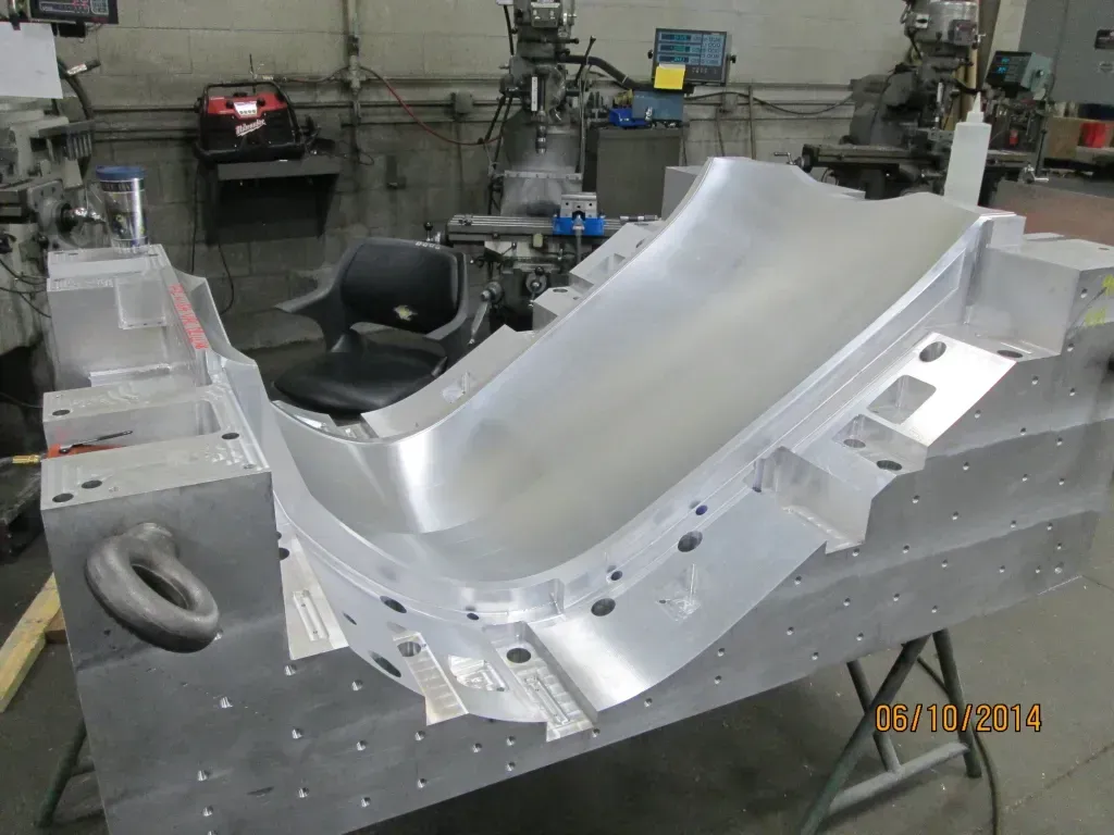 Large silver metal panel in a workshop, with tools and equipment in the background.
