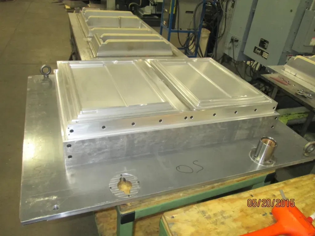 Metal industrial machine housing on a factory floor, with silver panels and a large flat base.