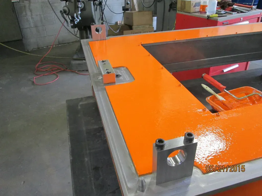 Orange industrial machine table with metal fixtures in a workshop
