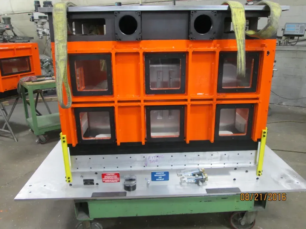 Orange industrial machine with black panels and gauges in a workshop setting