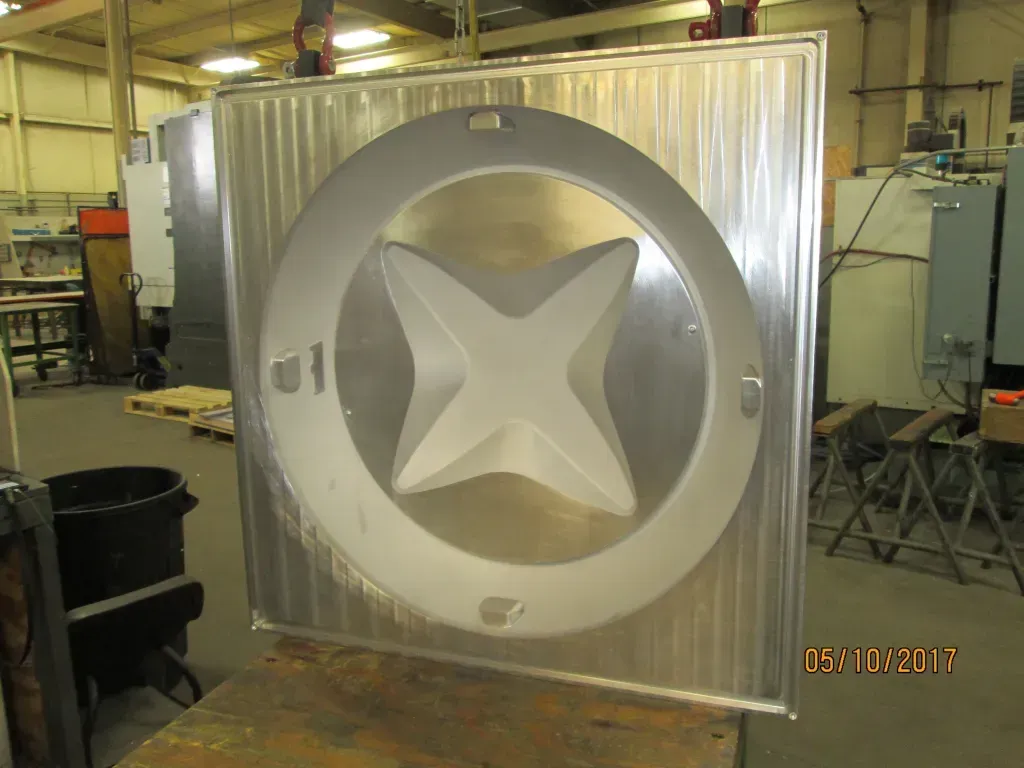 Large silver industrial metal tank with a star-shaped center, inside a workshop