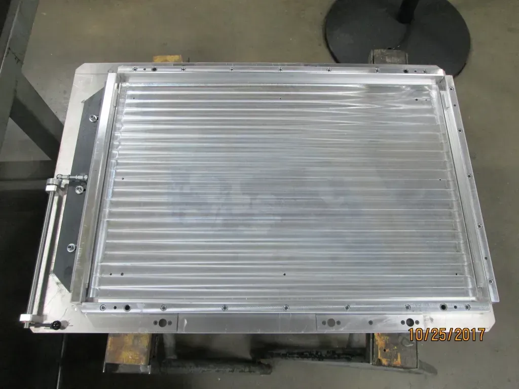 Rectangular silver metal panel with horizontal slats on a workshop floor