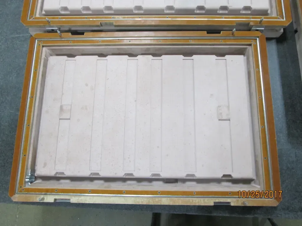 Open box with a white rectangular insert and transparent lid on a gray surface