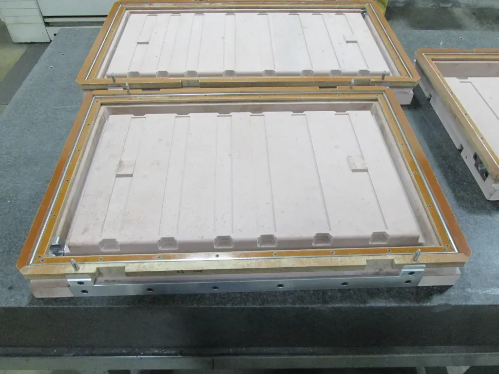 Open metal trays with white rectangular panels on a workbench