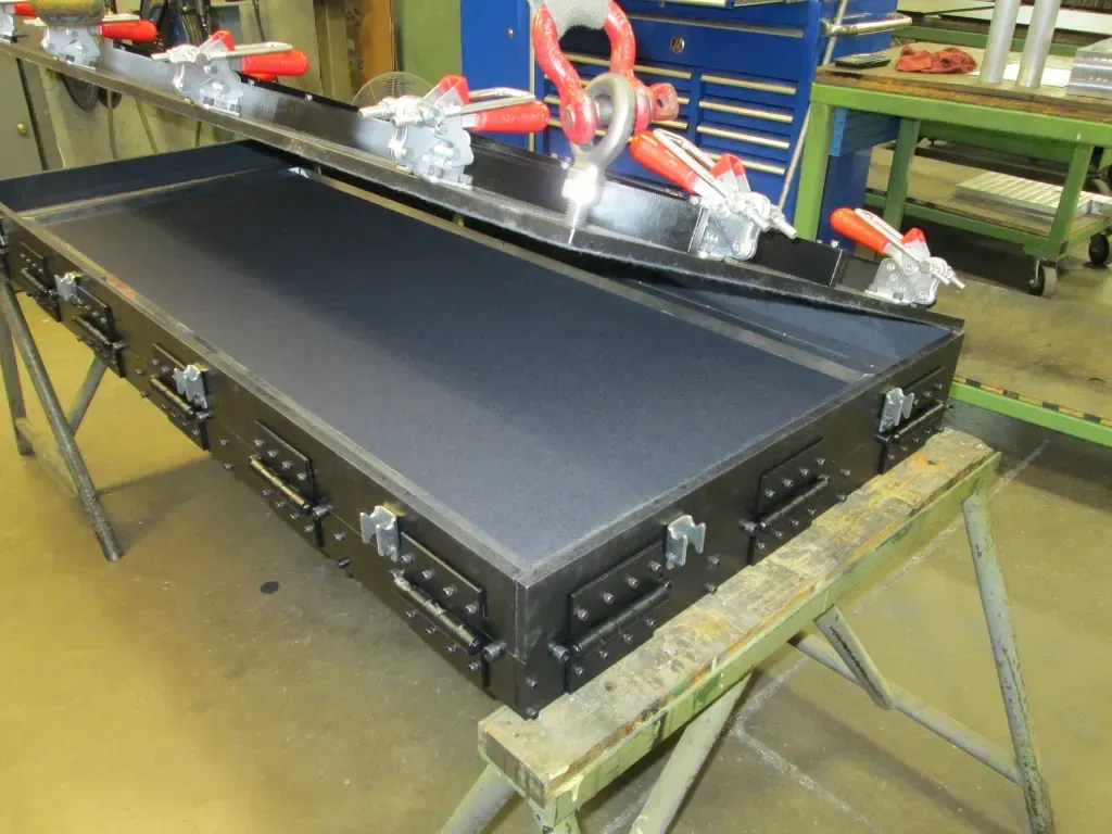 Industrial conveyor belt on a workshop bench with tools and parts along the top edge