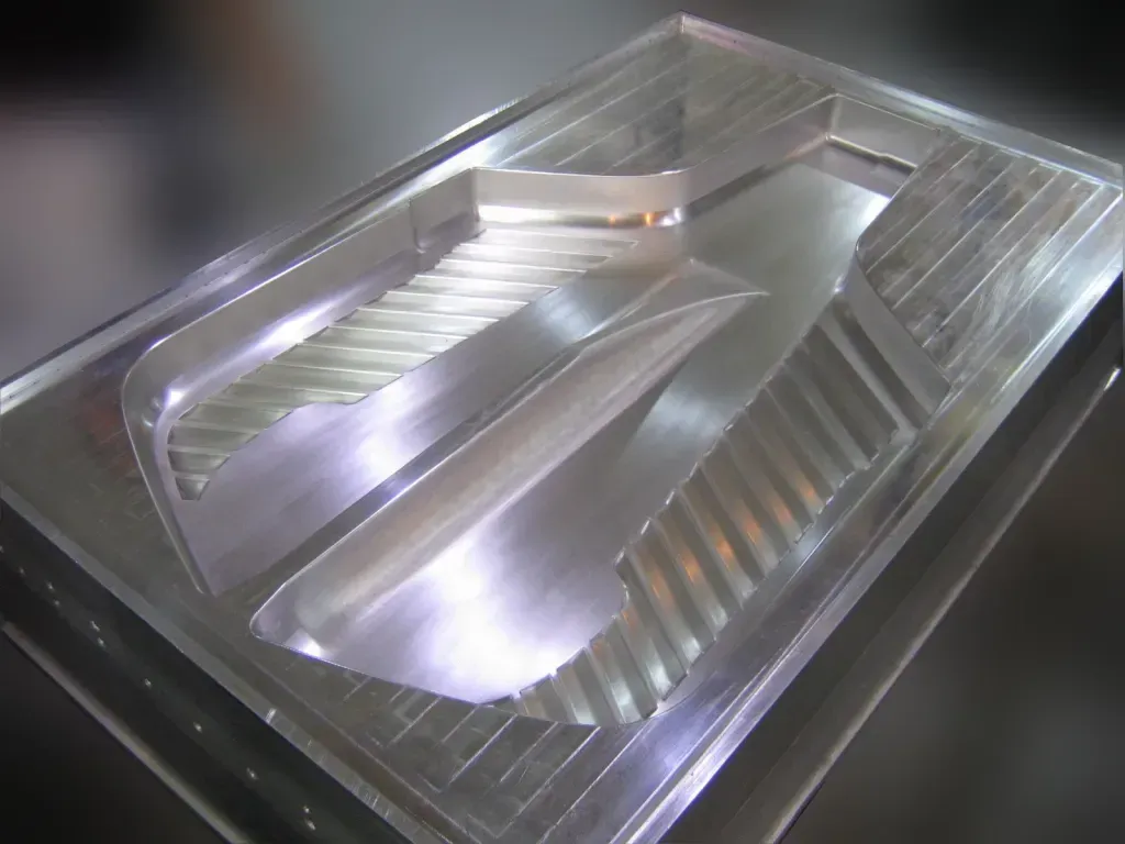Stainless steel metal mold with intricate stepped channels, viewed from above.
