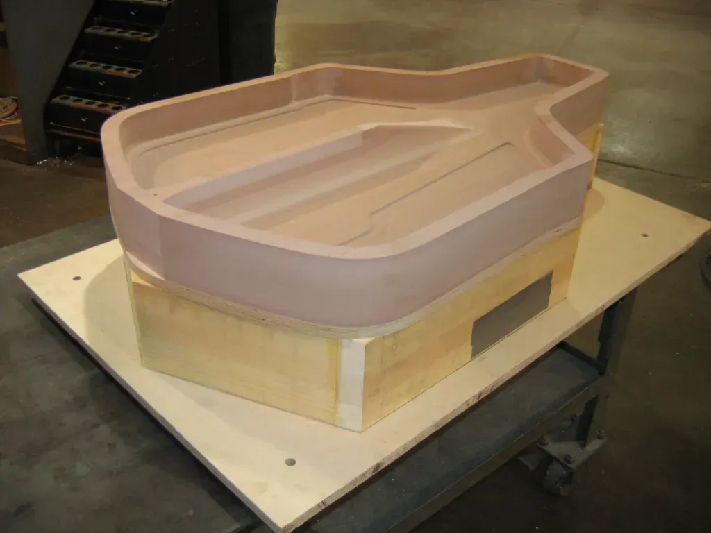 Wooden boat hull mockup on a workbench in a workshop