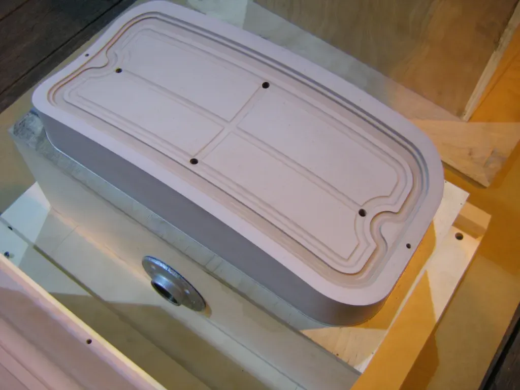 Rectangular plastic container with a white lid and small black fasteners on a wooden surface