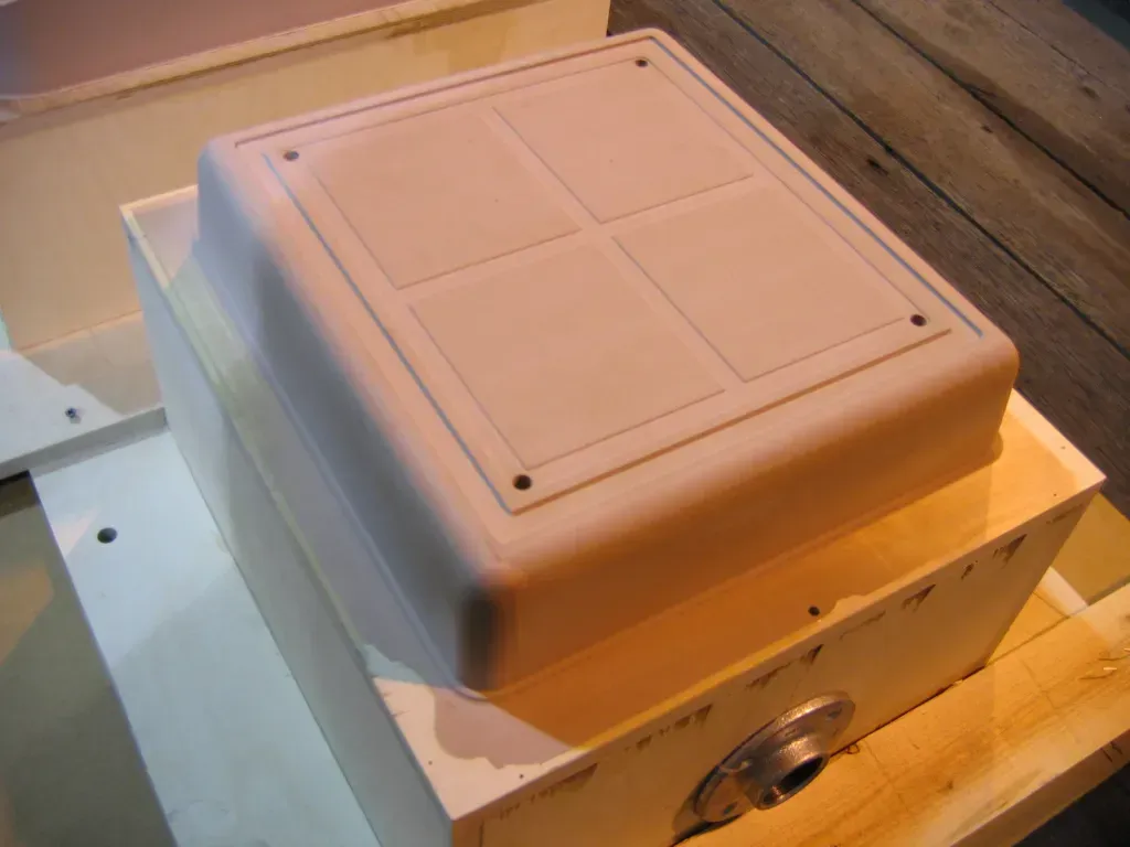 White plastic enclosure mounted on a metal box, viewed at an angle, with a beige top lid and knobs on the side
