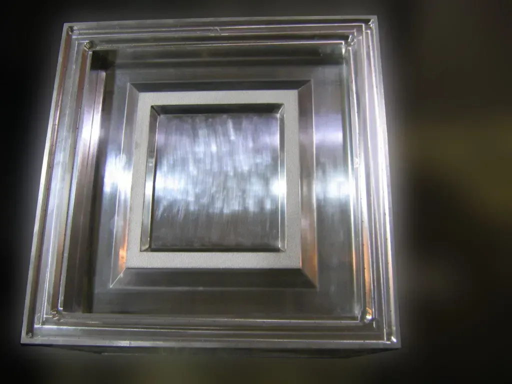 Square metallic air vent with a brushed silver center and reflective frame