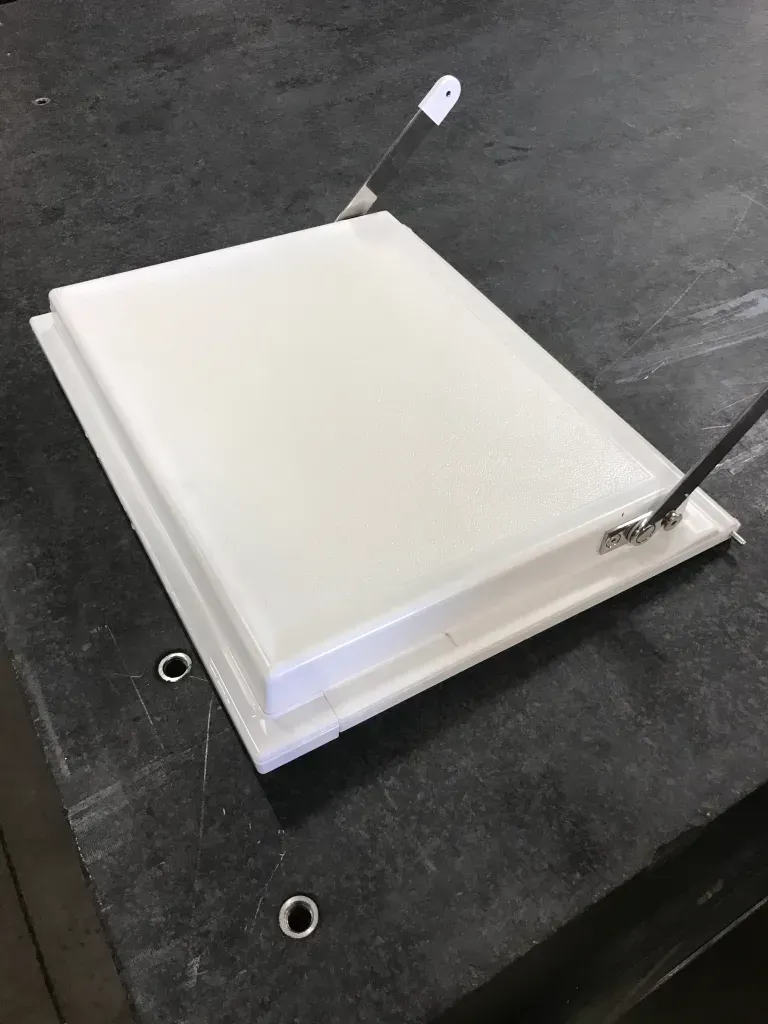 White square light panel on a dark surface with attached wires and mounting brackets