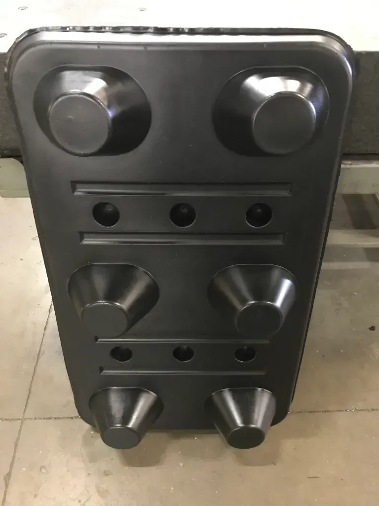 Black metal panel with six knobs and three small buttons, standing upright on a tiled floor.