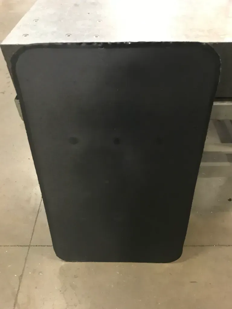 Black rectangular table or cabinet against a light tiled floor.